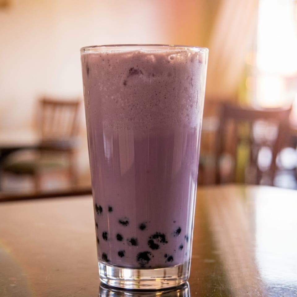 Refreshing glass of purple boba tea with dark pearls on a restaurant table.