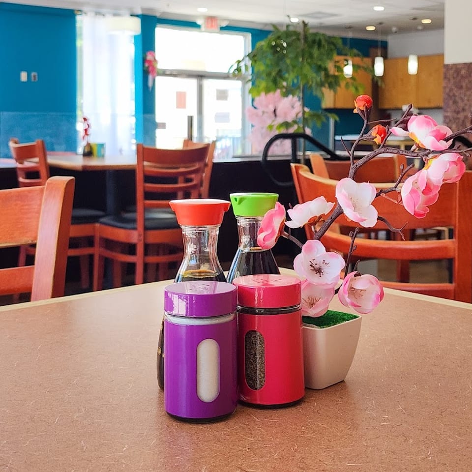 Table setting with soy sauce, shakers, and pink artificial cherry blossoms in a restaurant.