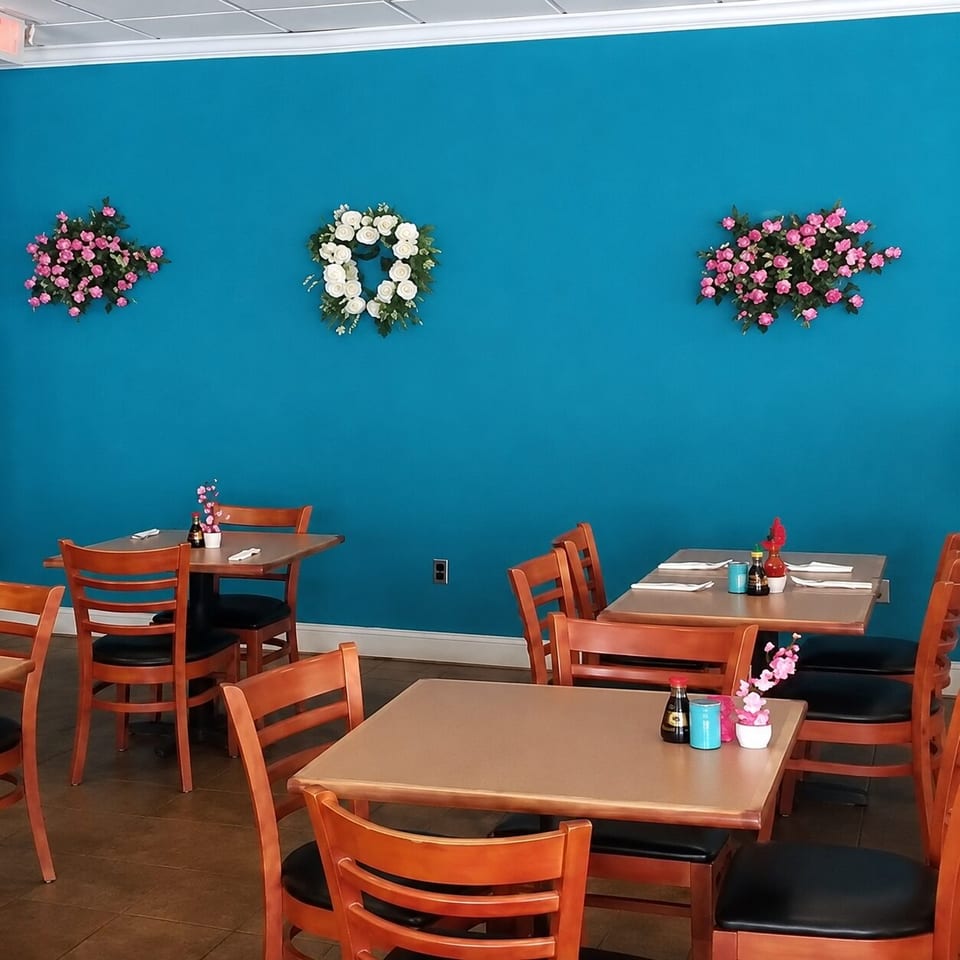 Vibrant blue restaurant dining room with wooden tables, chairs, and decorative floral wreaths.